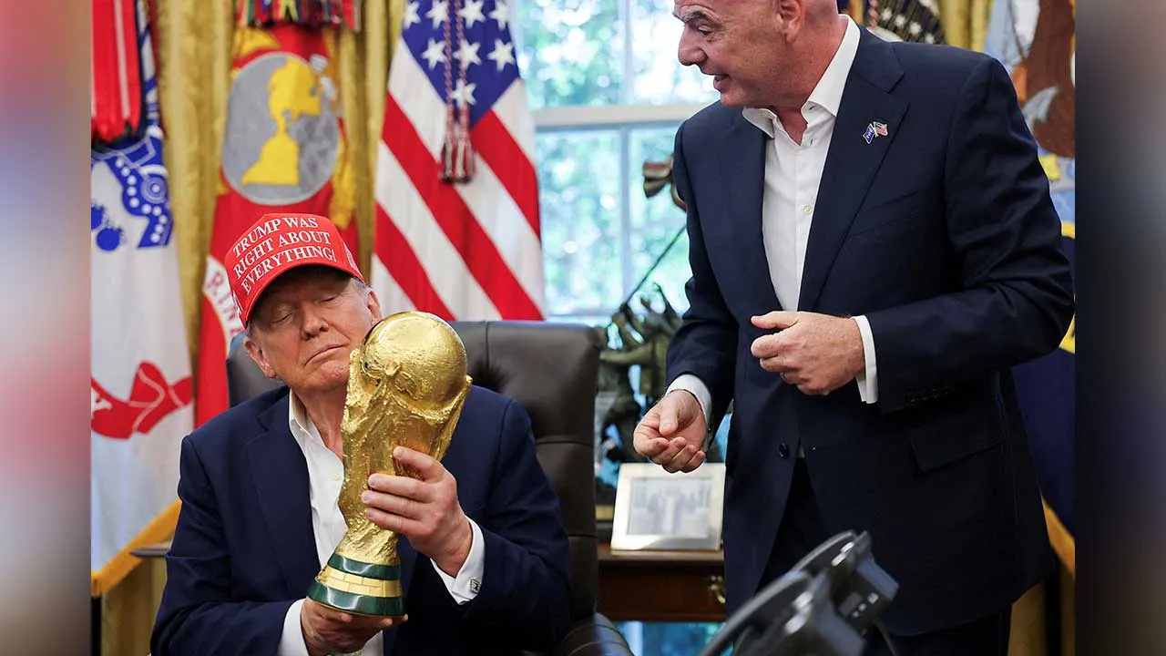 FILE PHOTO: U.S. President Donald Trump holds the FIFA World Cup Trophy, as he makes an announcement on the 2026 FIFA World Cup, as FIFA president Gianni Infantino stands next to him, in the Oval Office at the White House in Washington, D.C., U.S., August 22, 2025. REUTERS/Jonathan Ernst/File Photo