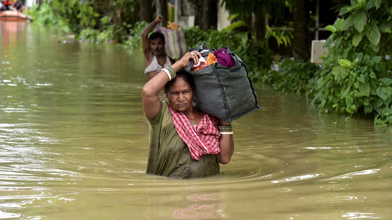 People wade through a flood-affected area with their belongings in Sivasagar, Assam, India, July 23, 2026. REUTERS/Hafiz Ahmed REFILE - QUALITY UPDATE TPX IMAGES OF THE DAY