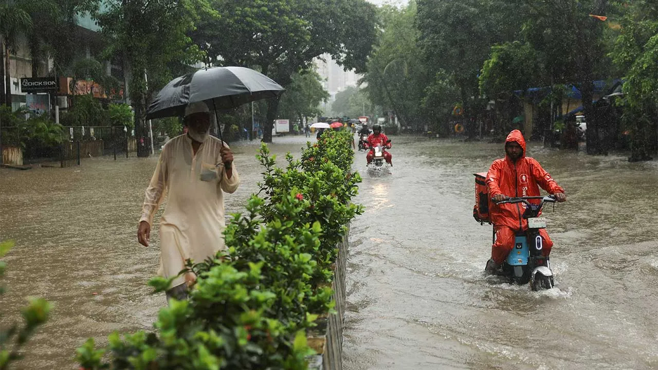 A man watches as gig workers ride through a waterlogged street after heavy rains in Mumbai, India, July 4, 2026. REUTERS/Francis Mascarenhas
