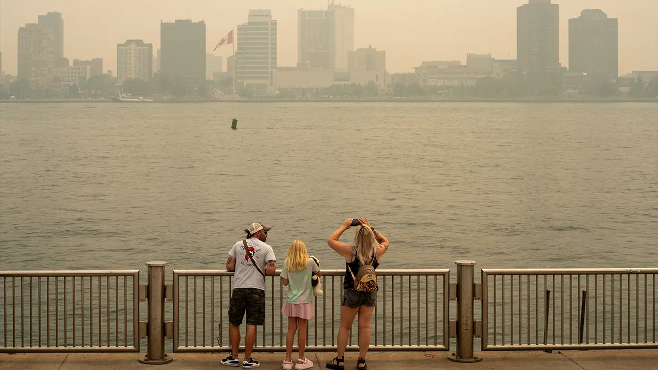 People look out as smoke from Canadian wildfires clouds a view of the Detroit River, which forms part of the international border between the United States and Canada, in Detroit, Michigan, U.S., July 16, 2026. REUTERS/David Peinado