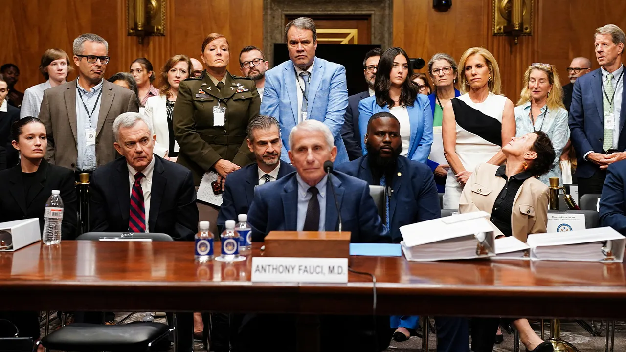 Members of the audience, who say they were negatively impacted by their skepticism to Covid-19 precautions, stand behind Anthony Fauci, the former Director of the National Institute of Allergy and Infectious Diseases (NIAID) and medical advisor to several U.S. presidents, at the urging of U.S. Senator Bernie Moreno (R-OH) at a U.S. Senate Homeland Security and Governmental Affairs Committee on Capitol Hill in Washington, D.C., U.S., July 29, 2026. Anthony Fauci declined to answer questions, invoking his Fif
