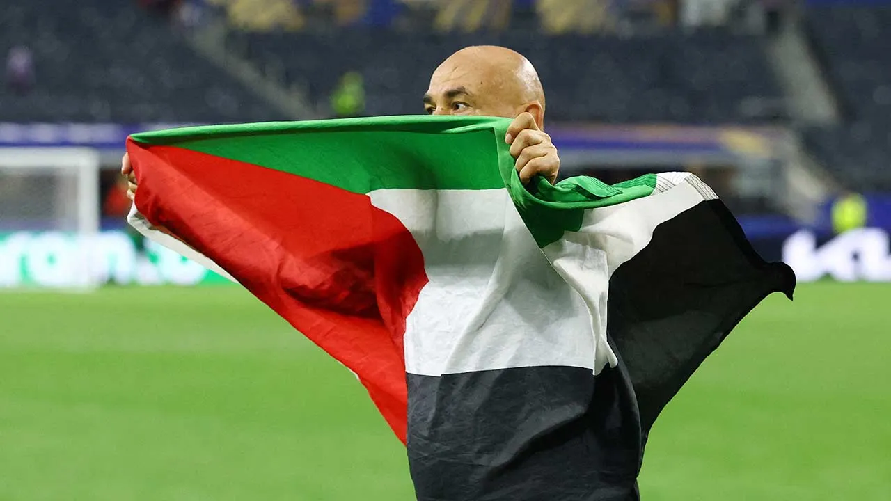 Soccer Football - FIFA World Cup 2026 - Round of 32 - Australia v Egypt - Dallas Stadium, Arlington, Texas, U.S. - July 3, 2026 Egypt coach Hossam Hassan celebrates with a Palestine flag after the match as Egypt qualify for the Round of 16 stage of the World Cup REUTERS/Hannah Mckay TPX IMAGES OF THE DAY