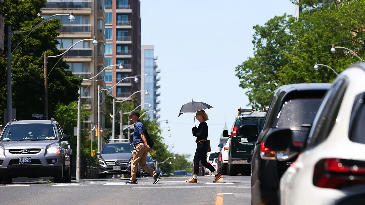 People cross a street in midtown Toronto amid a heatwave in the city on Tuesday, July 14, 2026. (Cole Burston/The Canadian Press via AP)