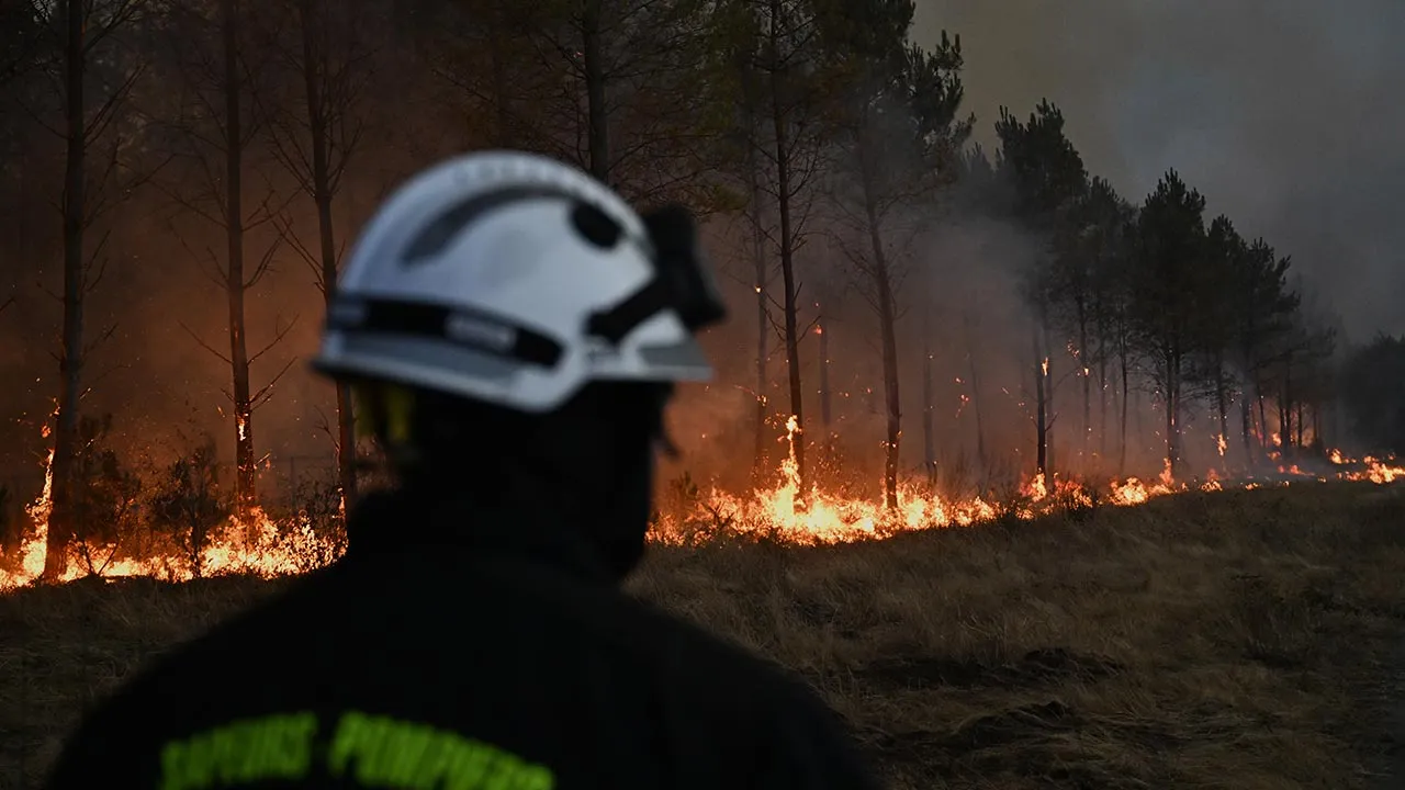 A firefighter walks in front of burning trees as a wildfire rages near Marcheprime, outside, Bordeaux, France, Sunday, July 26, 2026. (AP Photo/Emma Da Silva)
