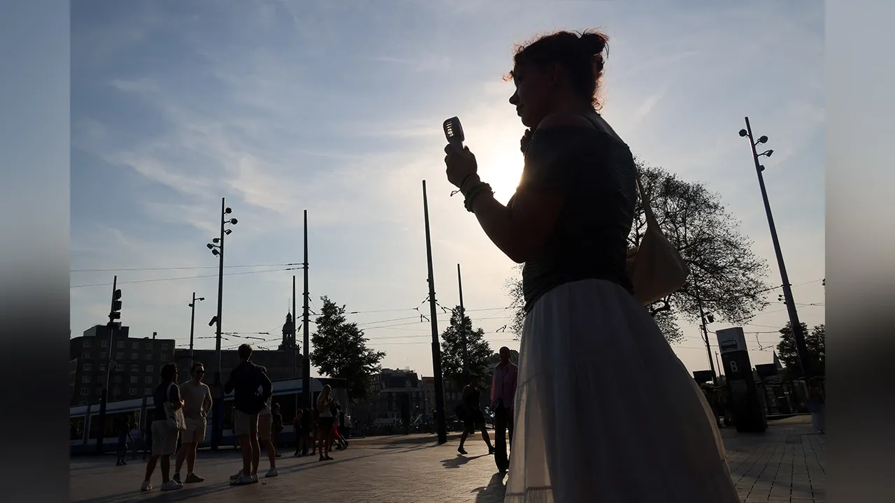 A woman is silhouetted as she holds a portable fan during a heatwave hitting the country, while a code red alert is issued, in Amsterdam, the Netherlands, June 26, 2026. REUTERS/Nicolas Economou