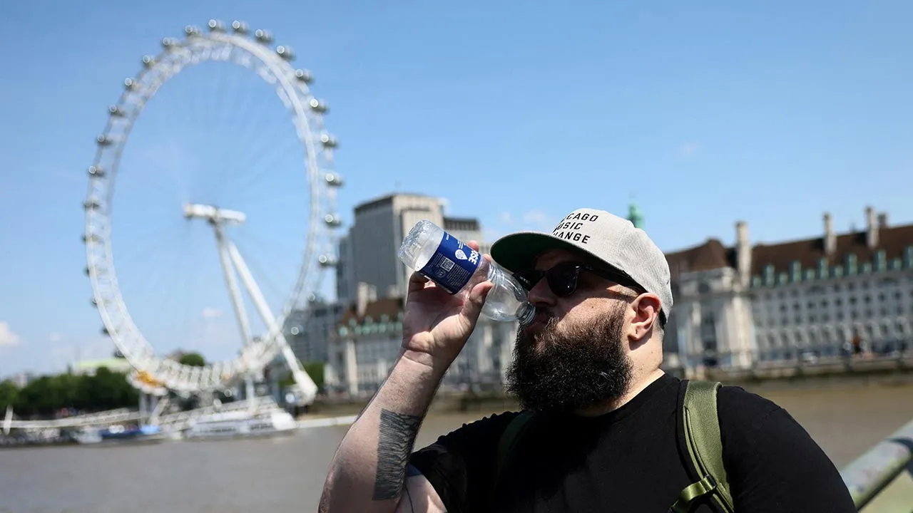 A man sips from a bottle of water as he walks down Westminster Bridge during the hot summer weather in London, Britain, June 19, 2026. REUTERS/Jack Taylor