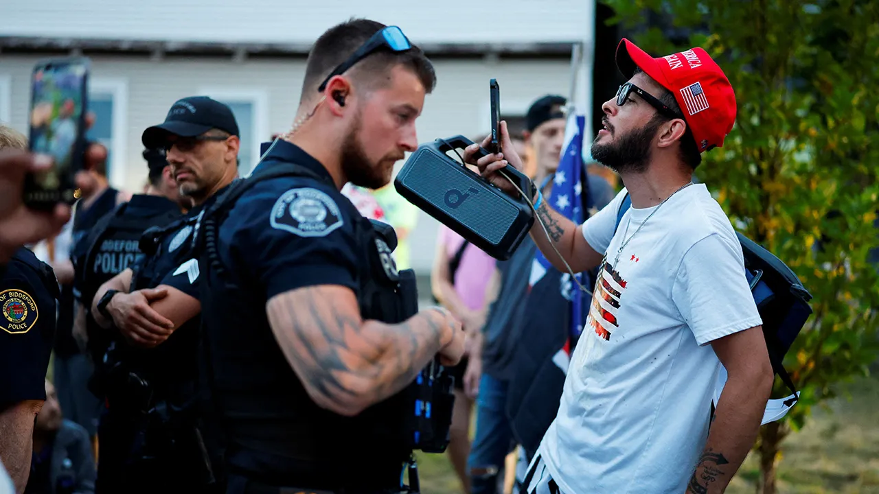 A counterprotester wearing a MAGA hat stands holding a speaker as people protest against U.S. Immigration and Customs Enforcement (ICE) at Mechanics Park, after a shooting involving ICE, in Biddeford, Maine, U.S., July 13, 2026. REUTERS/CJ Gunther