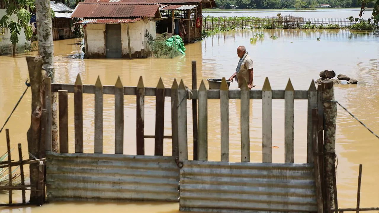 A man wades through the flood water near his submerged house in Teok village in upper Assam, India, Friday, July 24, 2026. (AP Photo/Parikhit Saikia)