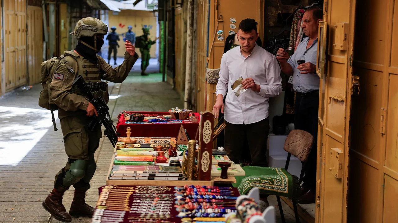 An Israeli soldier orders Palestinian shopkeepers to close their stall, during Israeli settlers' weekly tour in Hebron, in the Israeli-occupied West Bank, July 25, 2026. REUTERS/Mussa Qawasma