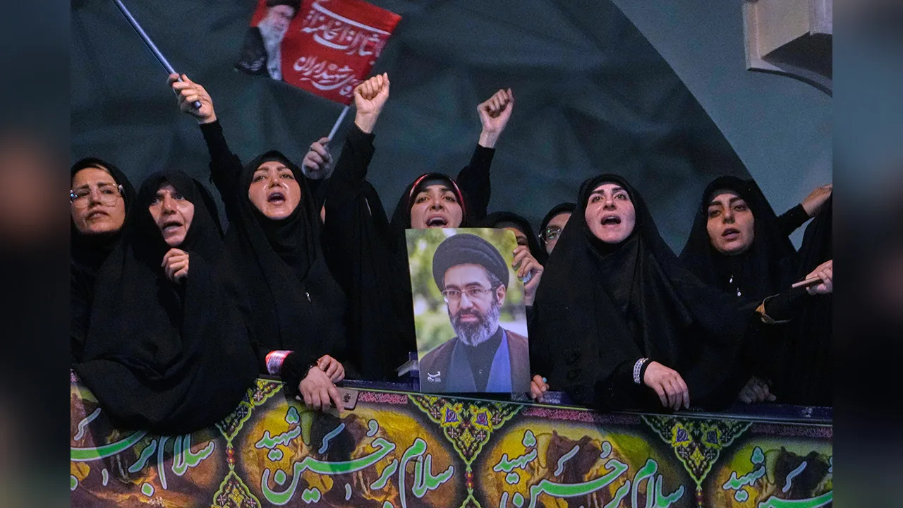 Mourners chant slogan as one of them holds a poster of the Supreme Leader Ayatollah Mojtaba Khamenei in a ceremony commemorating the late Supreme Leader Ayatollah Ali Khamenei at the Imam Khomeini Mosalla Grand Mosque in Tehran, Tuesday, July 14, 2026. (AP Photo/Vahid Salemi)
