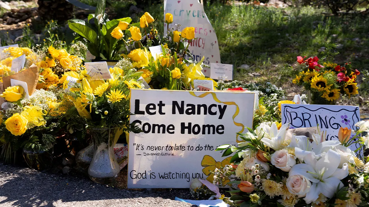 FILE PHOTO: A sign reads stands amid yellow flowers left at the house of Nancy Guthrie, the 84-year-old mother of U.S. journalist and television host Savannah Guthrie, who went missing from her home on February 1, in Tucson, U.S., February 21, 2026. REUTERS/Rebecca Noble/File Photo