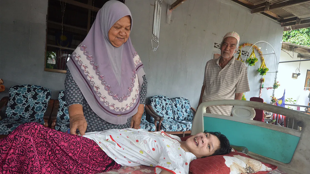 JERTIH, 22 Julai -- Pasangan warga emas, Halimah Said, 65, dan suaminya Mat Ail Mamat, 78, terpaksa menjaga anak mereka Rosnani, 41, yang terlantar sejak lahir seperti bayi di rumah mereka di Kampung Baru Tok Dor semalam.  Halimah berkata menguruskan Rosnani tidak ubah seperti menjaga bayi, malah dia terpaksa mendapatkan bantuan anak atau cucu untuk mengangkat Rosnani yang kini dianggar seberat sekitar 30 kilogram ke bilik air bagi tujuan membersihkan diri.  Warga emas itu berkata dia dan suami tidak lagi m
