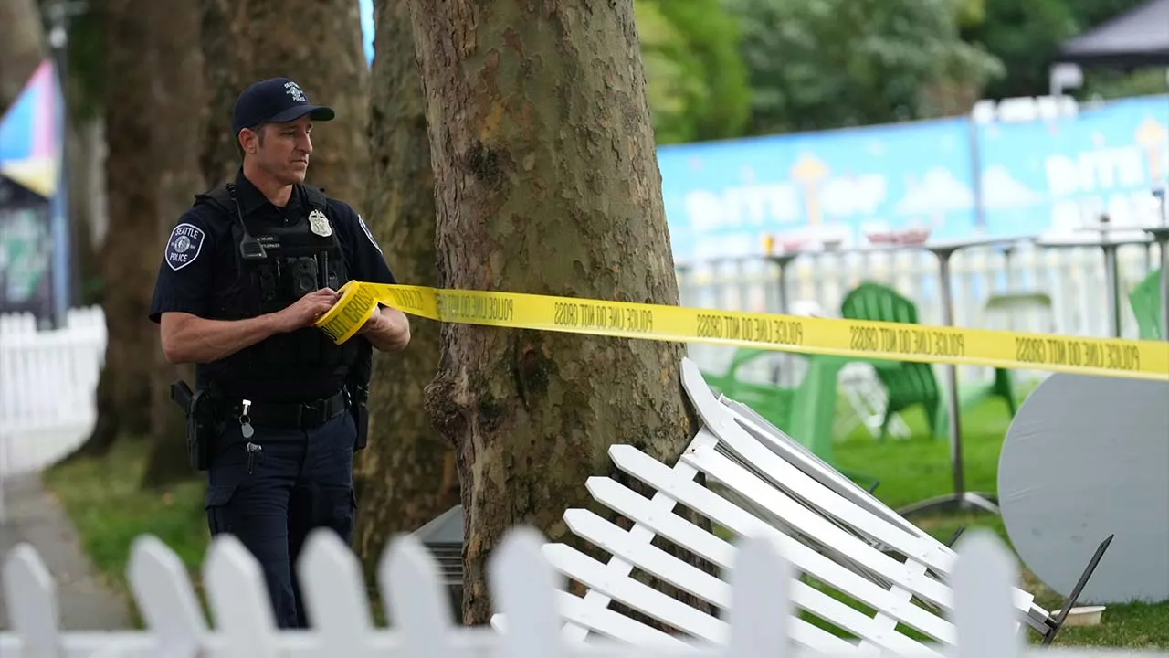 A Seattle Police officer sets up police line tape at the site of a shooting at Seattle Center during the Bite of Seattle food festival Sunday, July 26, 2026, in Seattle. (AP Photo/Lindsey Wasson)