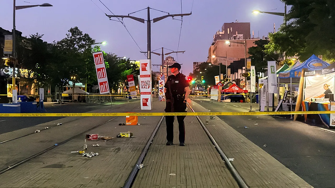 A police officer stands guard at the scene after a deadly shooting, at a salsa-themed street festival in Toronto, Ontario, Canada, July 11, 2026. Picture taken using a mobile phone. REUTERS/Cole Burston