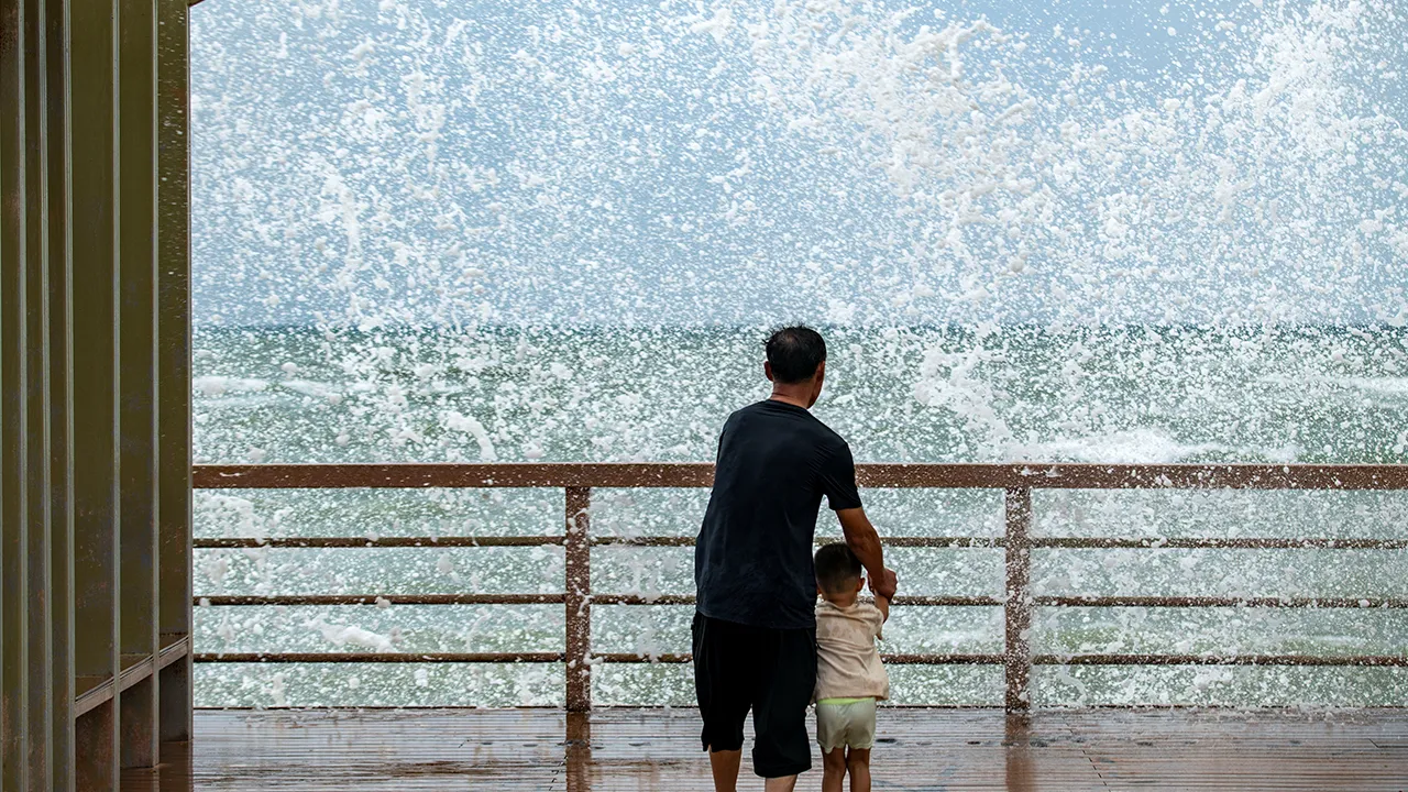 People watch waves crashing against the shore as Tropical Storm Maysak approaches in Boao, Qionghai, Hainan province, China, July 3, 2026_REUTERS