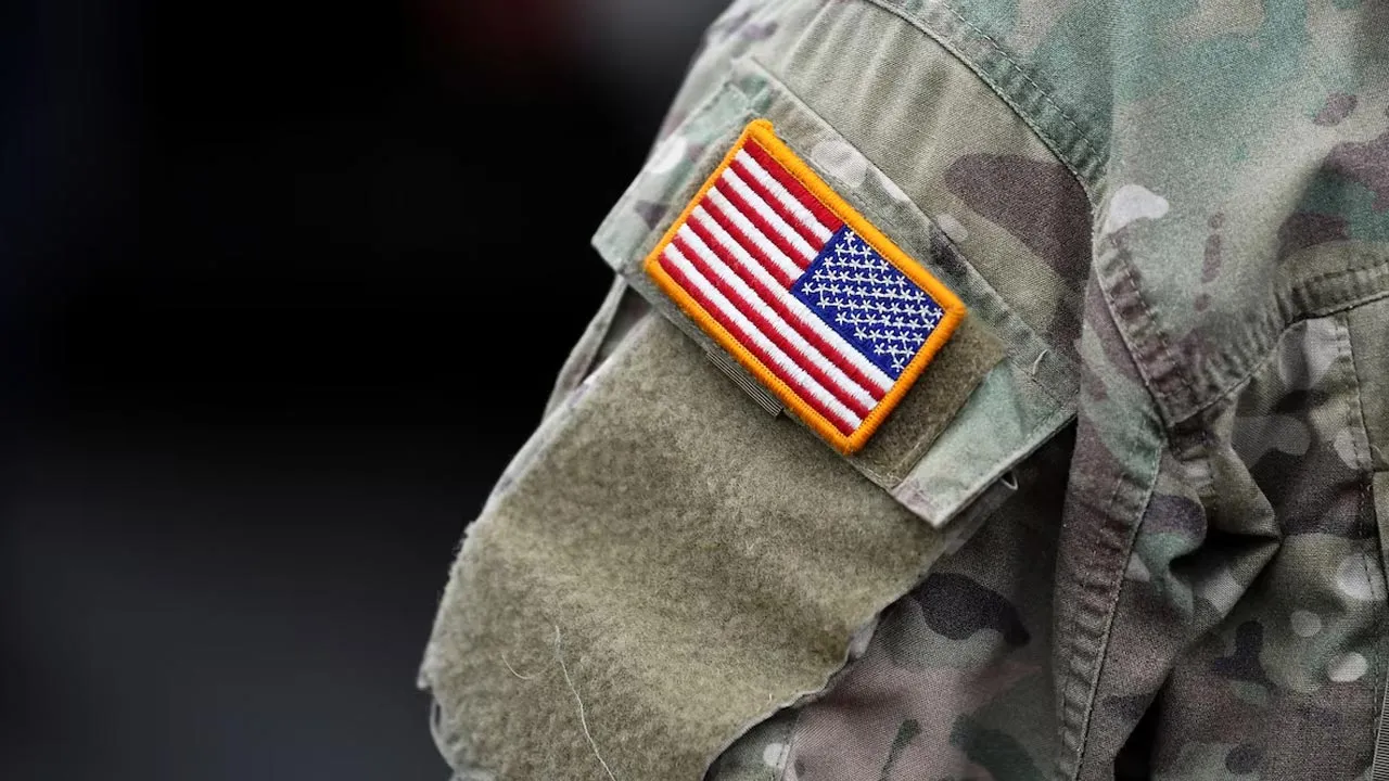 An U.S. flag is pictured on the arm of a soldier of the U.S. 2nd Cavalry Regiment as gear is prepared for deployment to Romania at Rose Barracks in Vilseck, Germany, February 9, 2022. REUTERS/Lukas Barth/File Photo