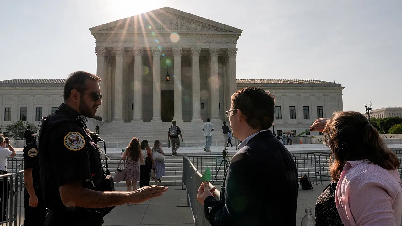 People speak to police officers in front of the Supreme Court building, as the court is set to issue the final rulings of its nine-month term, in Washington, D.C., U.S., June 30, 2026. REUTERS/Cheney Orr