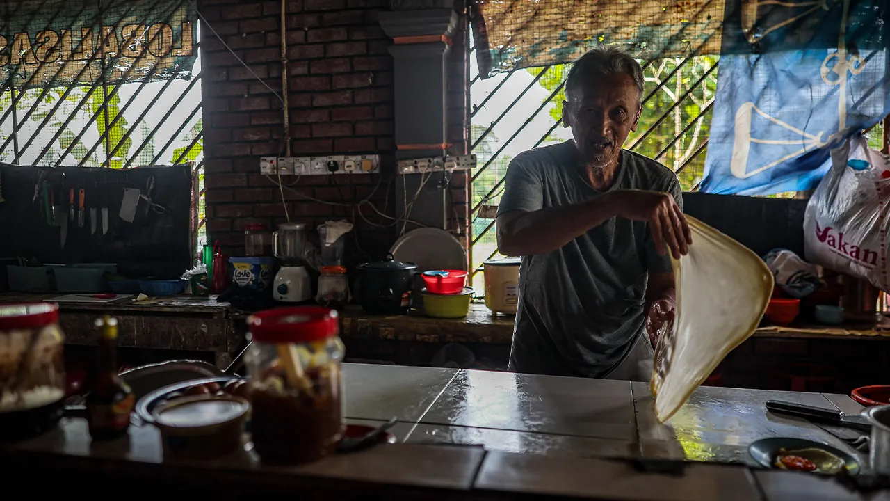 SIMPANG RENGGAM, 1 Julai -- Peniaga warung di Felda Layang-Layang, Bahari Madiran, 76, teruja menyaksikan pengunjung daripada pelbagai kaum, dan agama yang berkumpul di warungnya ketika berkempen di Kampung Layang - Layang.  Kehangatan kempen Pilihan Raya Negeri (PRN) Johor bukan sahaja menghidupkan suhu politik, malah turut membawa limpahan rezeki luar biasa buat peniaga kecil di sekitar kawasan Layang-Layang dan Simpang Renggam.  -- fotoBERNAMA (2026) HAK CIPTA TERPELIHARA