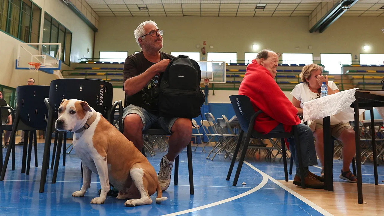 Moises, evacuated from the village of Asin, awaits with his dog Thor, at a municipal sports center turned into a temporary shelter in the town of Ejea de los Caballeros during efforts to battle wildfires affecting the Zaragoza province, Spain, July 17, 2026. REUTERS