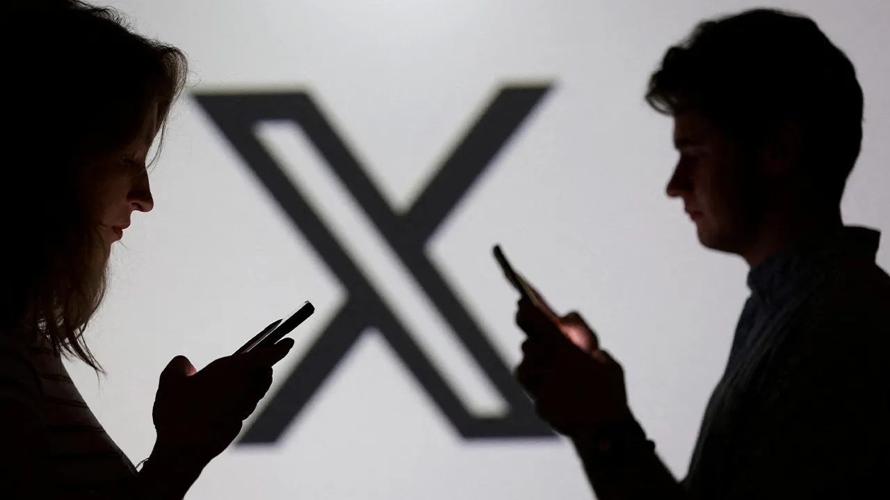 FILE PHOTO: Teenagers pose for a photo while holding smartphones in front of a X logo in this illustration taken September 11, 2025. REUTERS/Dado Ruvic/Illustration/File Photo