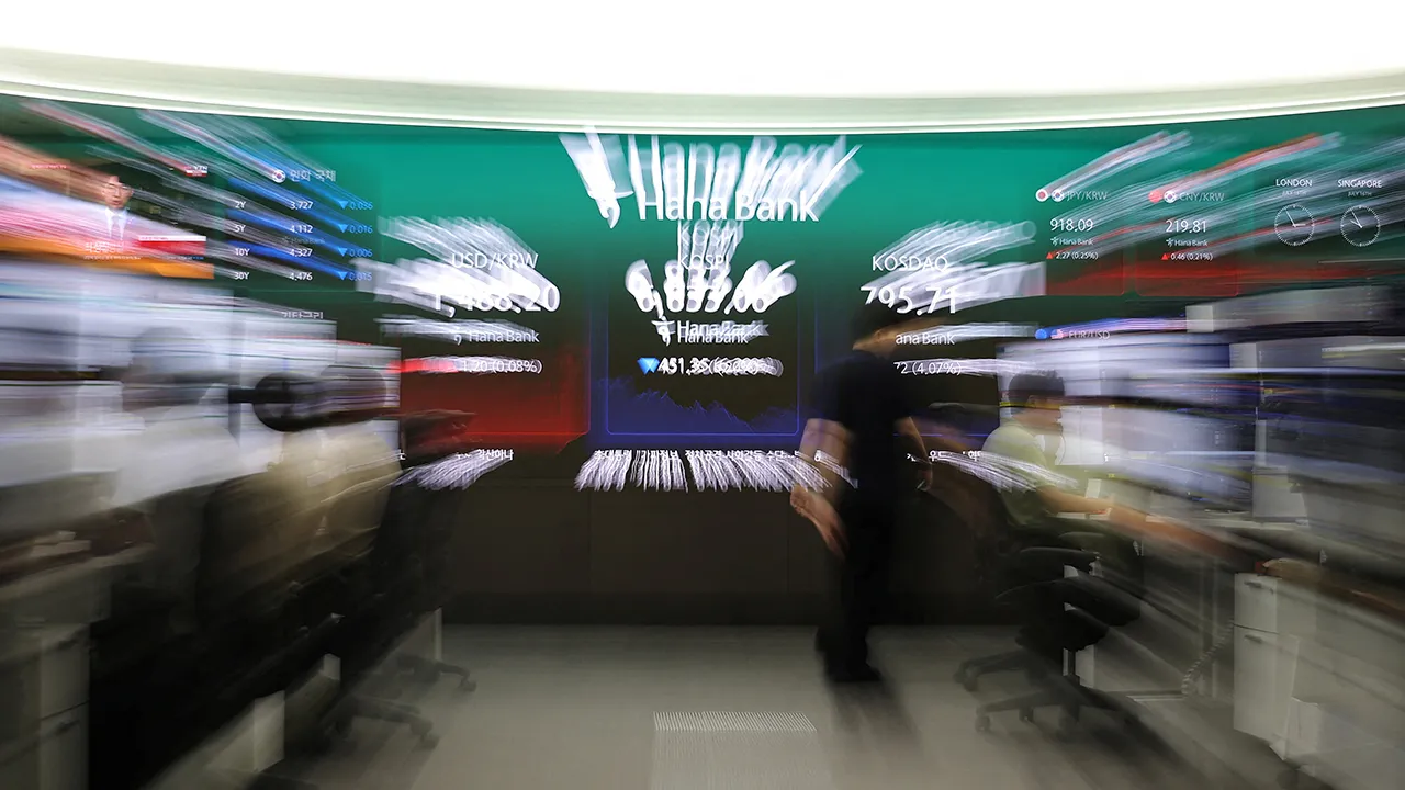 A currency dealer walks in front of an electronic board displaying the exchange rate between the U.S. dollar and South Korean won, the Korea Composite Stock Price Index (KOSPI) and the Korea Securities Dealers Automated Quotations (KOSDAQ) at the dealing room of a bank in Seoul, South Korea, July 16, 2026. REUTERS