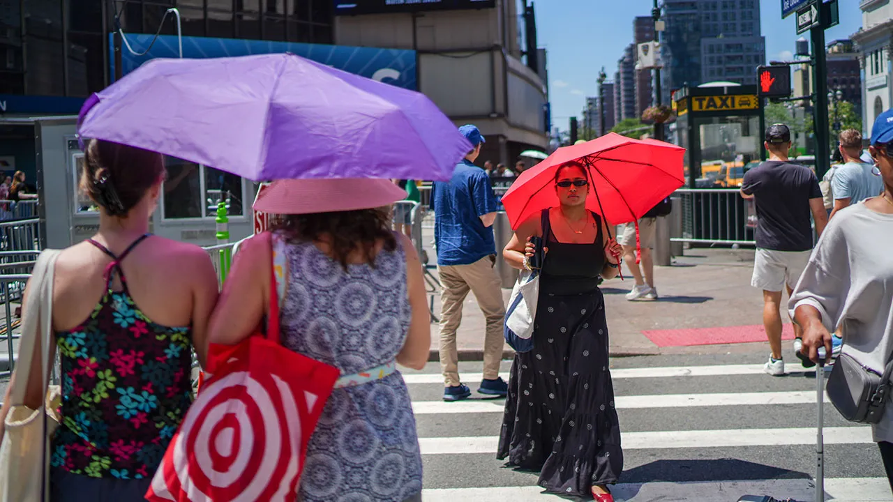 Pedestrians using umbrellas to block the sun, cross a street next to Madison Square Garden during an extreme heatwave in New York on Friday, July 3, 2026. (AP Photo/Ryan Murphy)