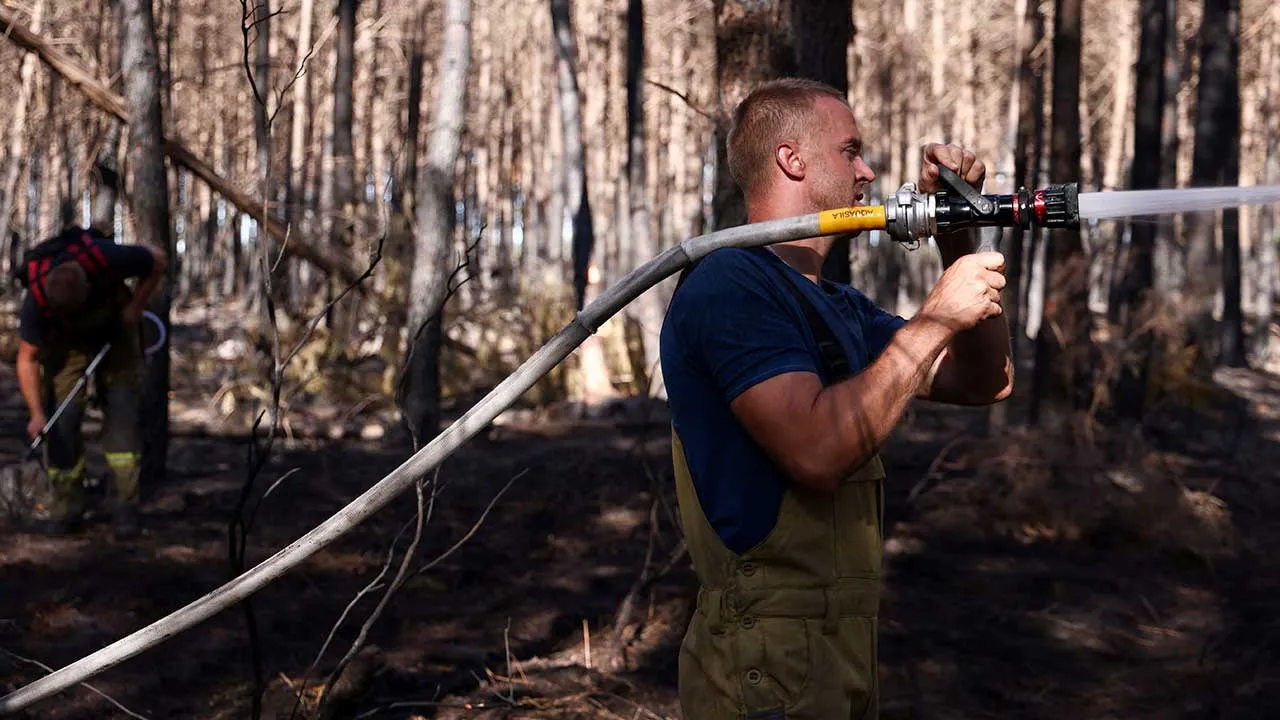 Ukrainian firefighter Misha sprays water on a wildfire area near Le Temple, Gironde, amongst worsening drought conditions following a heatwave and water shortages across much of France, August 7, 2026. REUTERS/Nicolas Economou