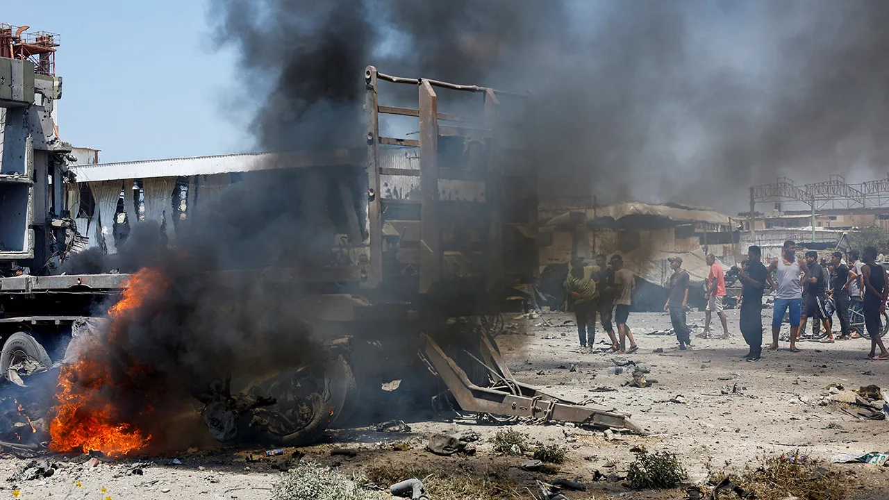 Fire burns next to a damaged flatbed trailer, as Palestinians gather close by, after an Israeli strike, carried out after the Israeli military warned residents to evacuate the area, Al-Zawayda, in the central Gaza Strip, August 23, 2026. REUTERS/Mahmoud Issa