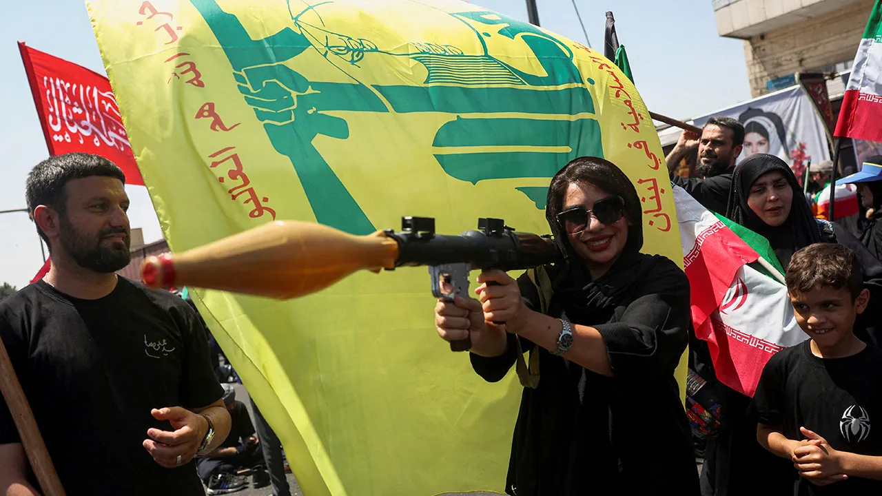 A woman holds a mock-up of a rocket-propelled grenade (RPG) next to a Hezbollah flag during the Arbaeen rally in Tehran, Iran, August 4, 2026. Majid Asgaripour/WANA (West Asia News Agency) via REUTERS