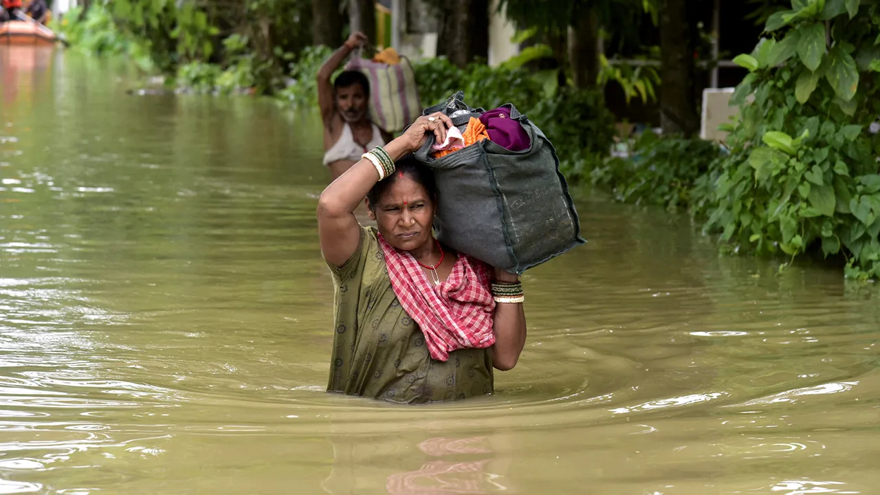 FILE PHOTO: People wade through a flood-affected area with their belongings in Sivasagar, Assam, India, July 23, 2026. REUTERS/Hafiz Ahmed/File Photo