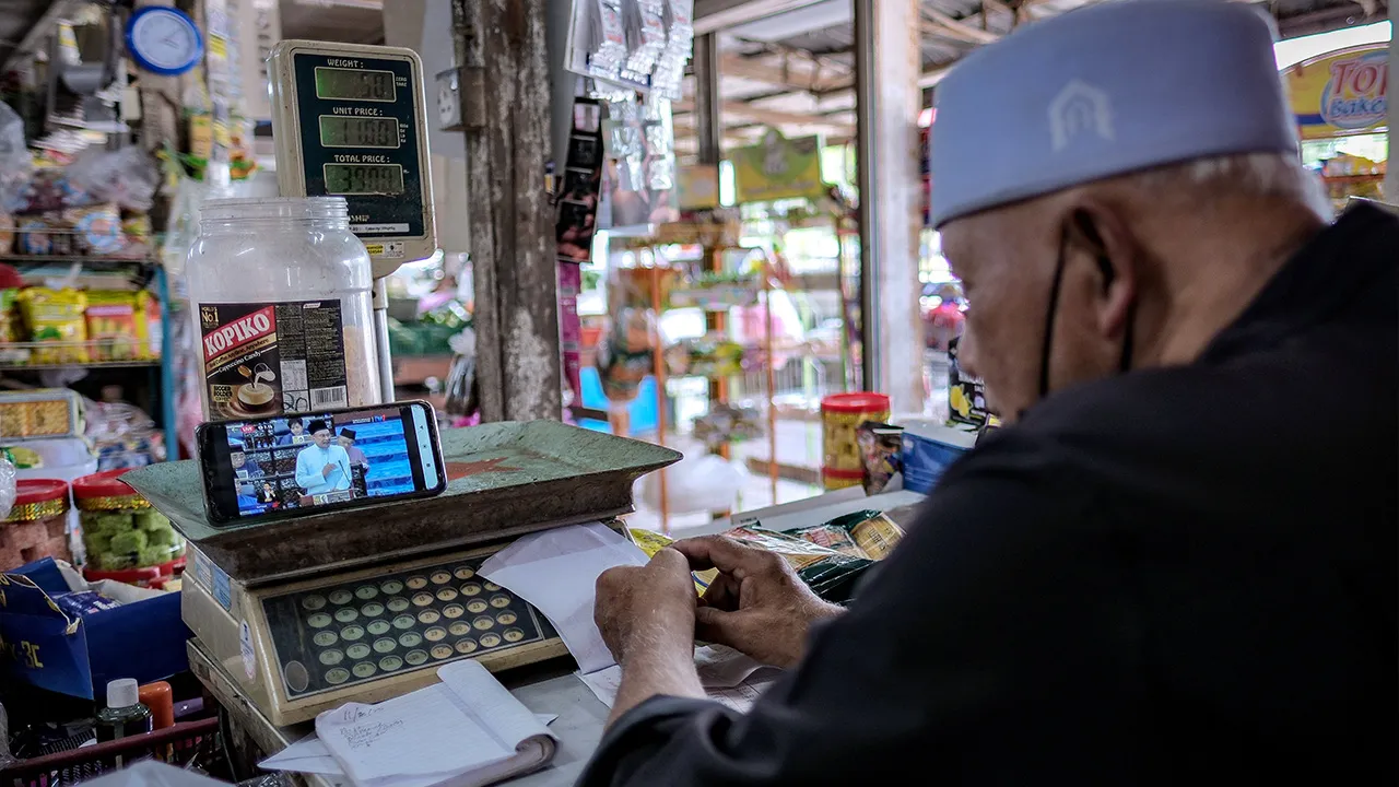 PONTIAN, 10 Okt -- Pengusaha kedai runcit, Kadiron Padrono, menonton siaran langsung pembentangan Belanjawan 2026 yang disampaikan oleh Perdana Menteri, Datuk Seri Anwar Ibrahim, di Kedai D’Pengkalan, Pontian, hari ini._BERNAMA