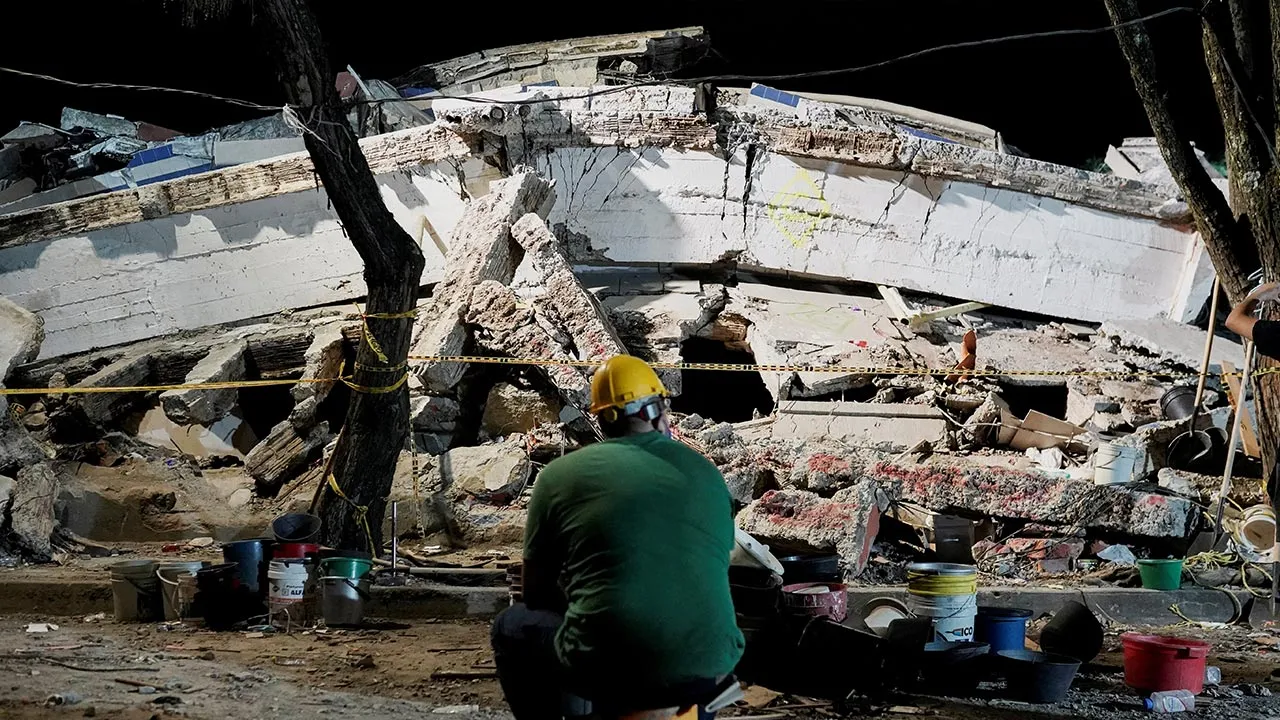 A man sits near debris at the Torres de Limonar building in the aftermath of an earthquake, in Cali, Colombia, August 11, 2026. REUTERS/Sergio Acero