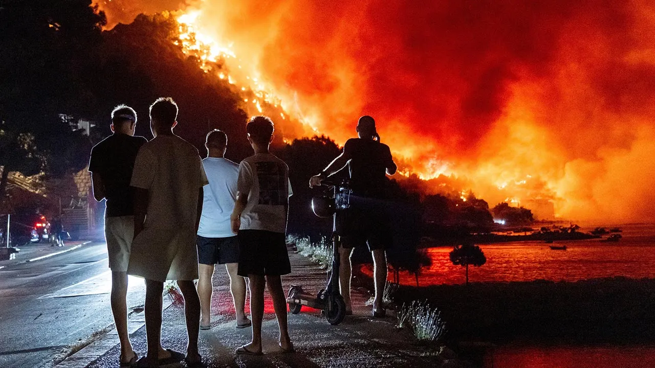People look at a wildfire on the Adriatic coast near Omis, southern Croatia, early Friday, Aug. 14, 2026. (AP Photo/Tom Dubravec)