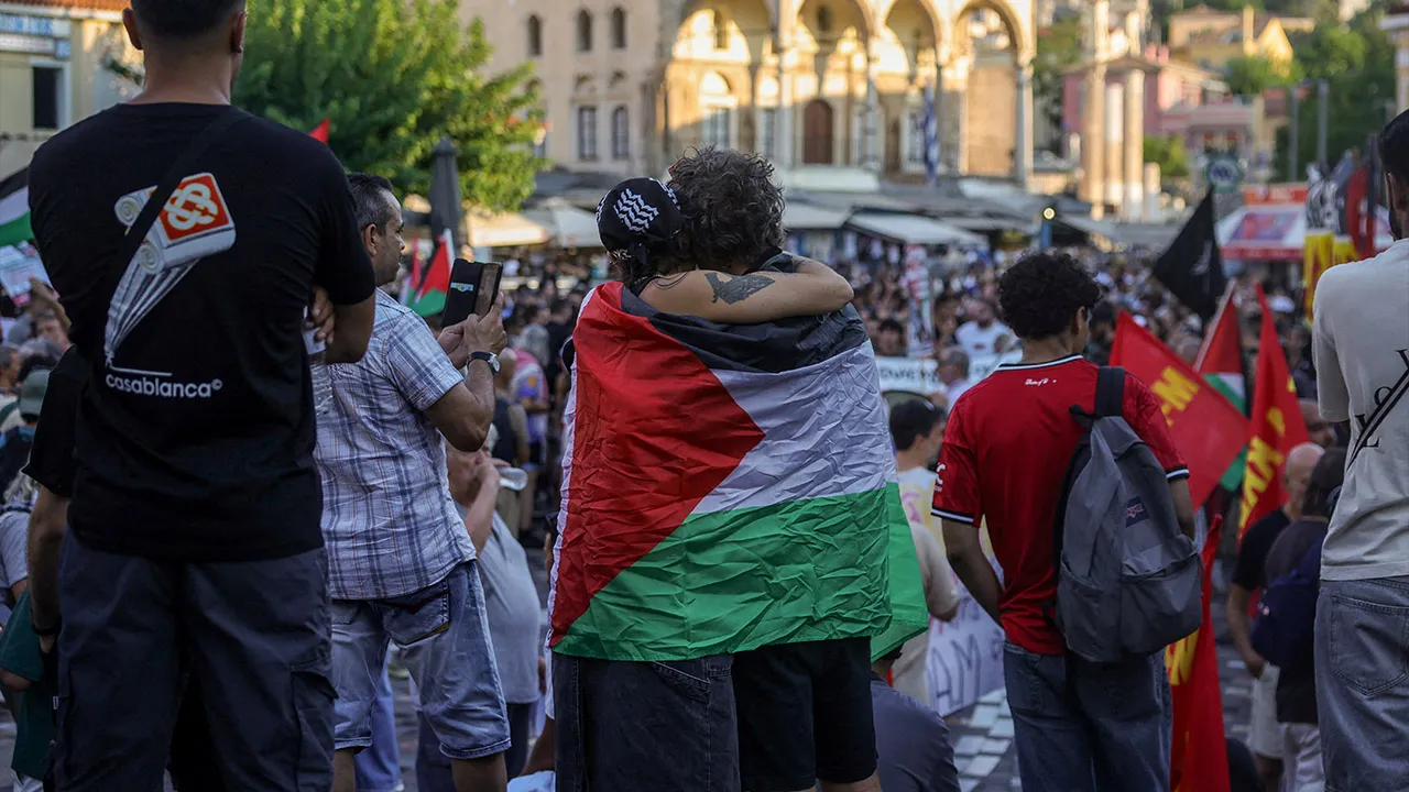 A couple embraces wrapped in Palestinian flag , as activists and pro-Palestinian supporters gather at city's touristic Monastiraki square, as part of nationwide "Day of Action for Palestine" calling the authorities for sanctions against Israel and the revocation of visa-free entry for Israelis, in Athens, Greece, August 9, 2026. REUTERS/Louisa Gouliamaki