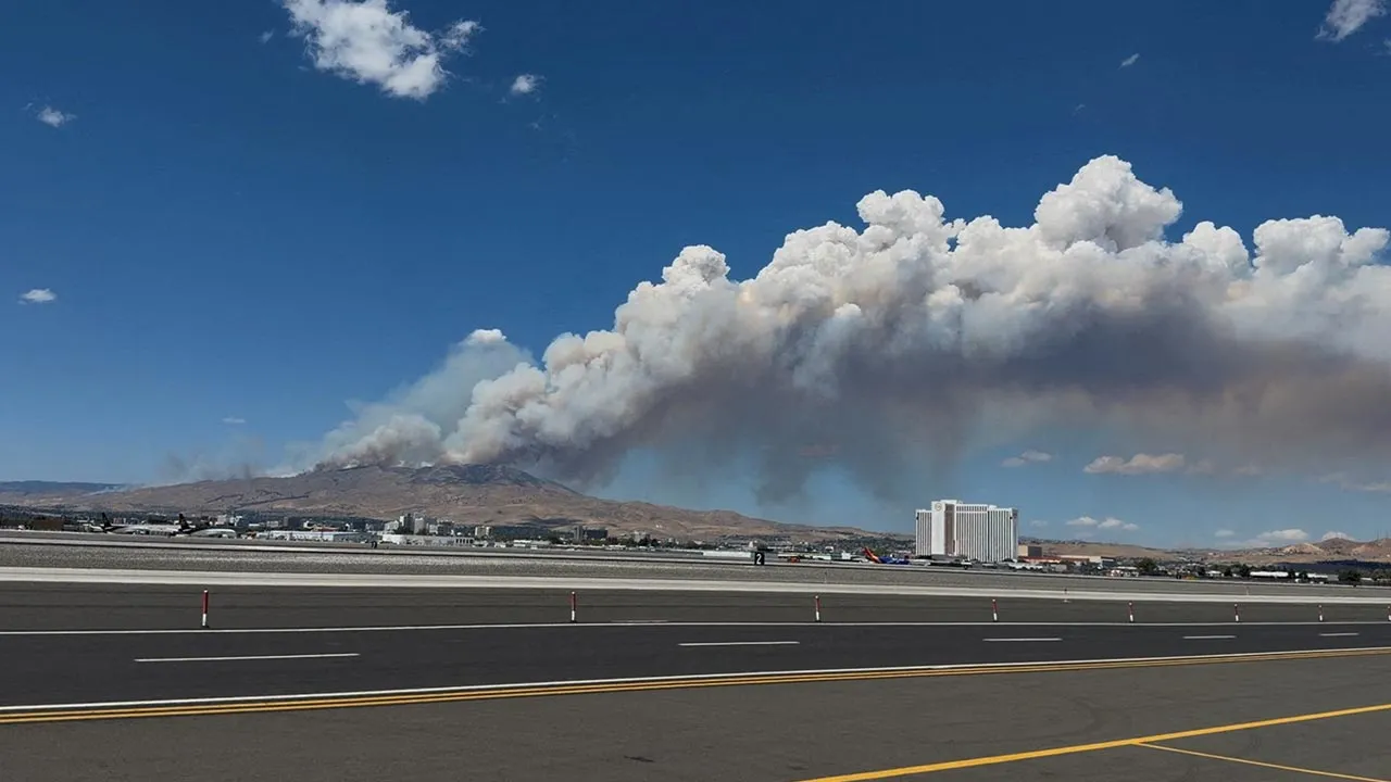 Smoke rises from hills during the Hawk Fire burning in Washoe County, Nevada, U.S., August 22, 2026 in this screengrab taken from a social media video. Kate Rouch/via REUTERS THIS IMAGE HAS BEEN SUPPLIED BY A THIRD PARTY. MANDATORY CREDIT. NO RESALES. NO ARCHIVES. VERIFICATION: -Location and date verified from original file metadata. - Buildings, airport airfield, mountain in the background and a waterbody match satellite imagery