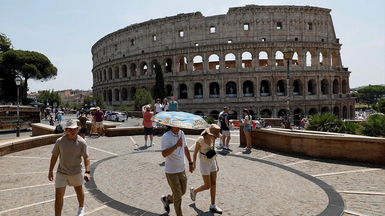 A person holds an umbrella as people walk near the Colosseum during a heatwave across Italy, as temperatures are expected to rise further in the coming days, in Rome, Italy August 3, 2026. REUTERS