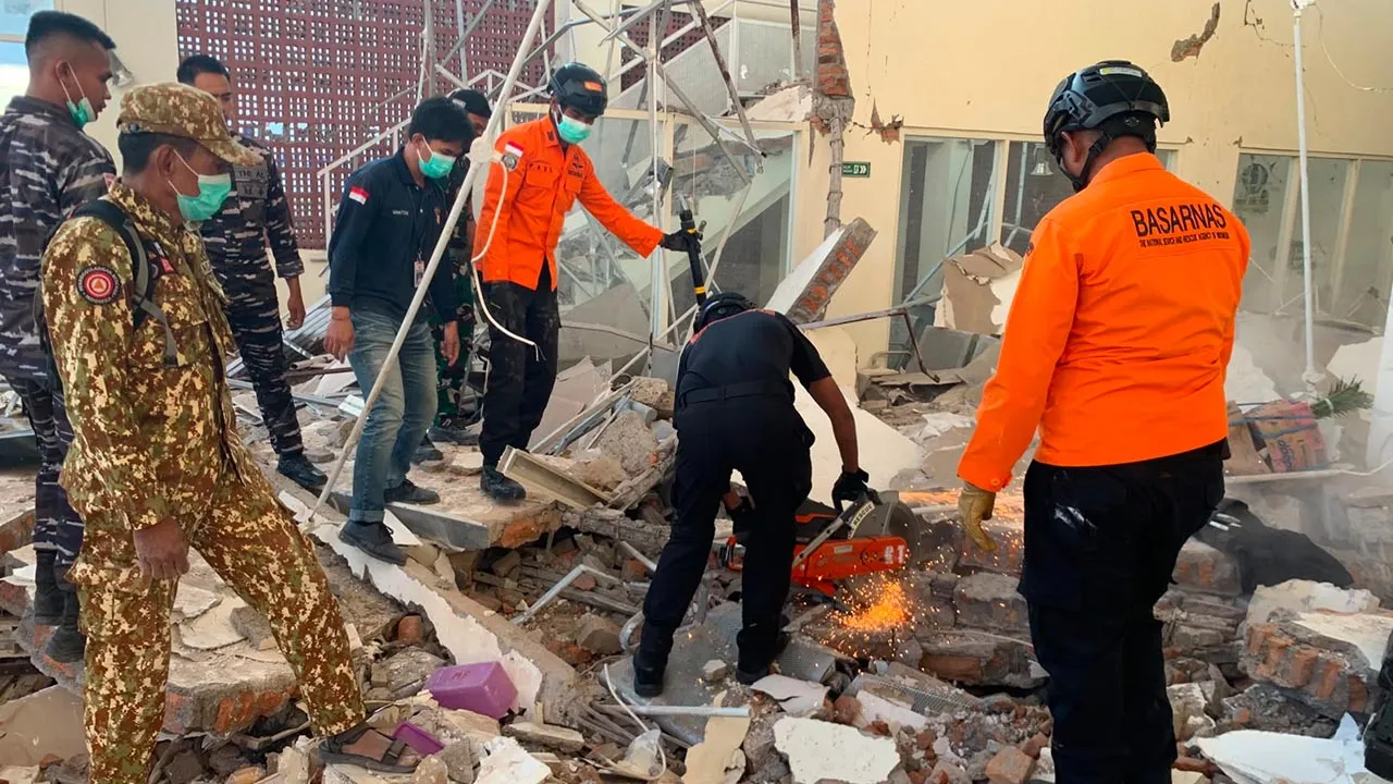 In this photo released by the Indonesian National Search and Rescue Agency (BASARNAS), rescuers attempt to clear debris at building damaged by an earthquake in Maumere, East Nusa Tenggara Province, Indonesia, Saturday, Aug. 15, 2026. (BASARNAS via AP)