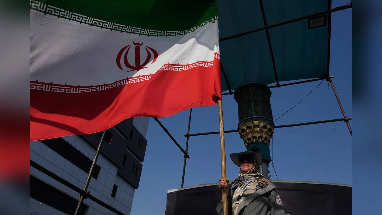 A woman holds an Iranian flag as part of a pro-government campaign in downtown Tehran, Iran, Monday, Aug. 17, 2026. (AP Photo/Vahid Salemi)