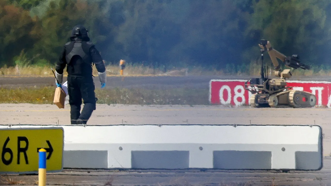 FILE PHOTO: A police officer in protective clothing walks next to an explosive-disarming robot (EOD) at Leipzig/Halle Airport in Schkeuditz, Germany, August 5, 2026, after the police said explosives experts examined a drone found near a runway, and after a DHL cargo aircraft hit an unknown object as it was climbing away from the airport overnight, prompting an unscheduled landing in Hanover, according to a source familiar with the incident. REUTERS/Axel Schmidt/File Photo