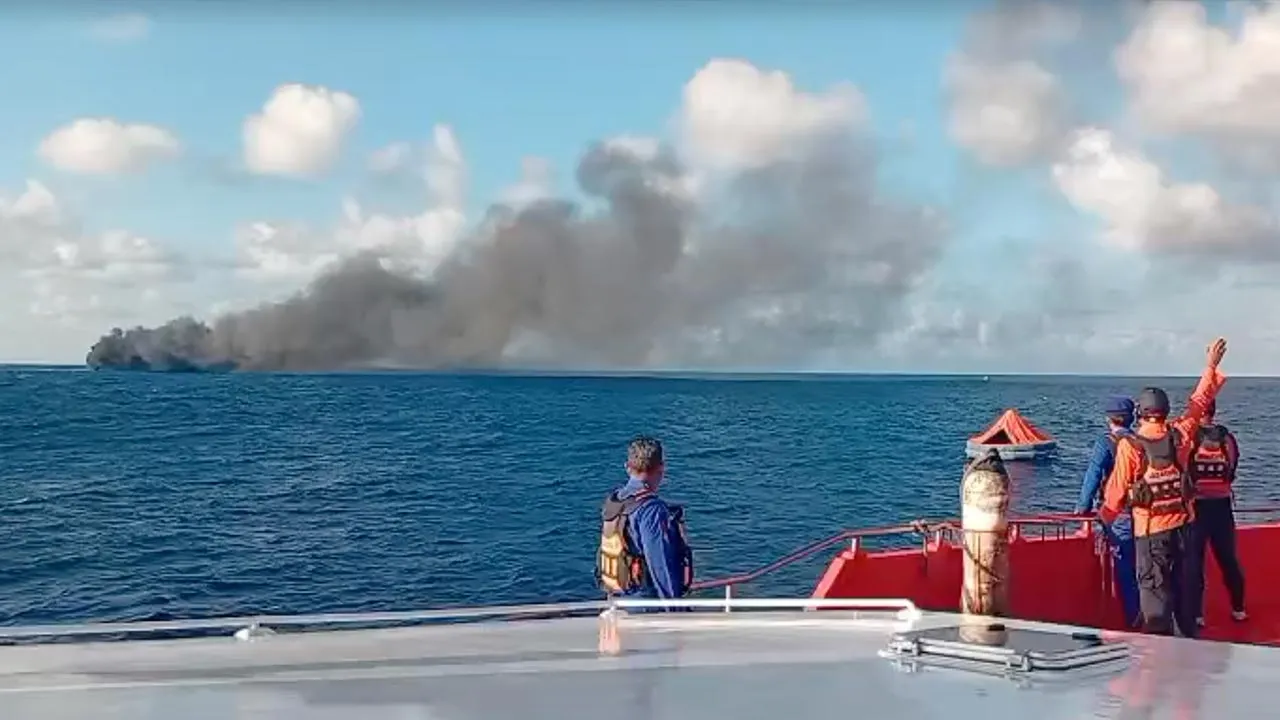 In this image made from video released by the Indonesian National Search and Rescue Agency (BASARNAS), the crew of a rescue ship look on as smoke billows from a passenger ferry that caught fire while traveling from the tourist island of Bali to neighboring island of Lombok, in the waters of Lombok Strait, Indonesia, Wednesday, Aug. 12, 2026. (BASARNAS via AP)