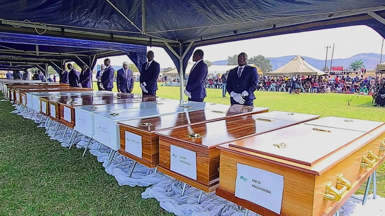 A pallbearer stands next to a line of coffins during a memorial service for victims of a Rural Infrastructure Development Agency (RIDA) passenger ferry that capsized on Lake Kariba, at Nyamhunga Stadium in Kariba, Zimbabwe, August 13, 2026. The ferry capsized on Tuesday, leaving multiple people dead. REUTERS/Bright Charakupa