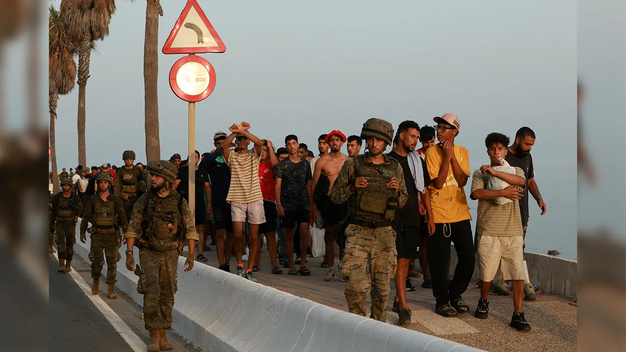 Members of the military escort migrants in Ceuta, Spain, following recent mass crossings of migrants on foot and by sea from Morocco into Spanish territory, August 1, 2026. REUTERS/Violeta Santos Moura TPX IMAGES OF THE DAY