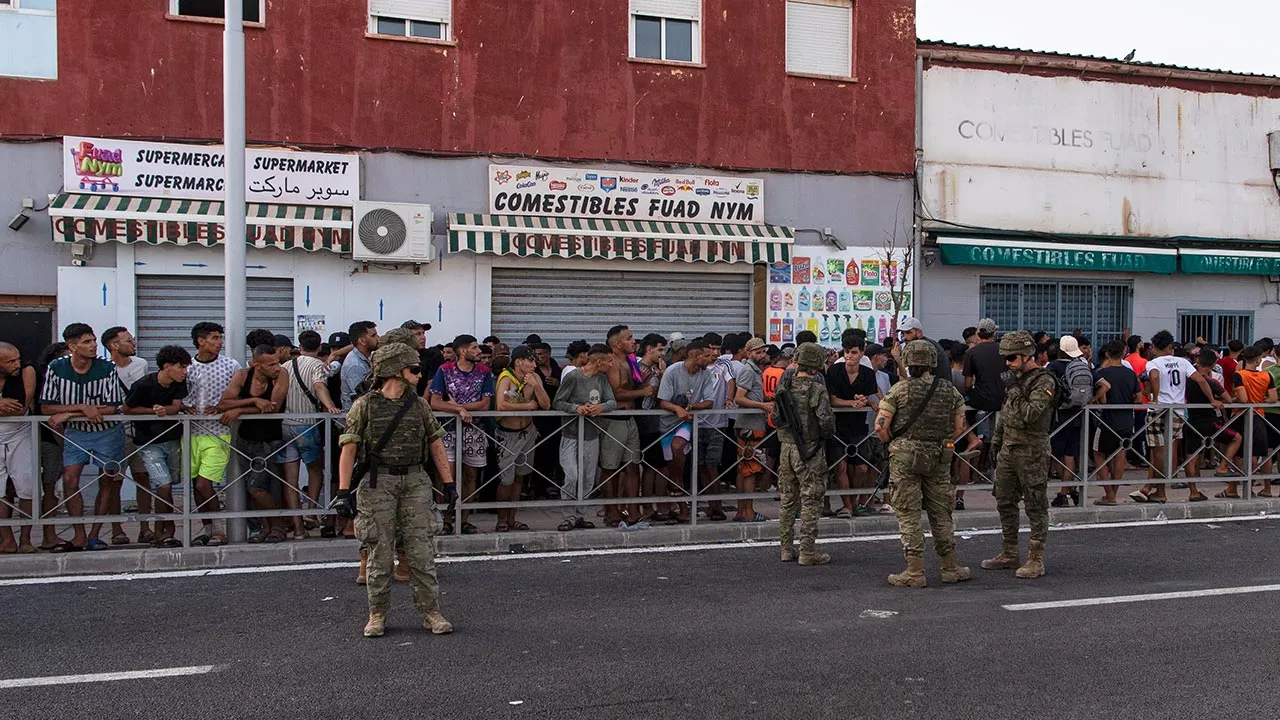 Migrants wait for a shop to open so they can buy food after crossing from Morocco into the Spanish enclave of Ceuta, Friday, July 31, 2026. (AP Photo/Antonio Sempere)