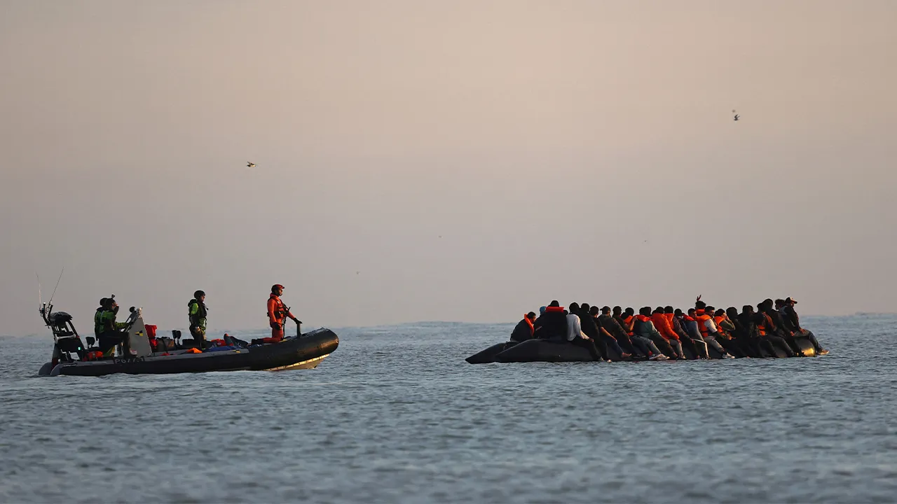 FILE PHOTO: French gendarmes on a boat approach a group of migrants on an inflatable dinghy to accompany them as they leave the coast of northern France in an attempt to cross the English Channel to reach Britain as tougher migration controls were announced, from the beach of Petit-Fort-Philippe in Gravelines, near Calais, France, July 17, 2025. REUTERS/Gonzalo Fuentes/File Photo