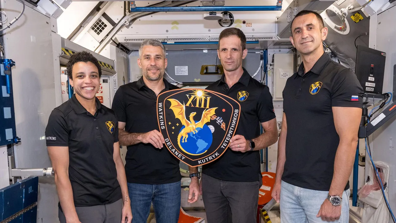 jsc2026e406664 (Aug. 5, 2026) — The four members of NASA’s SpaceX Crew-13 mission to the International Space Station display their mission plaque inside a training mockup of a space station module. From left are, Commander Jessica Watkins and Pilot Luke Delaney, both from NASA, and Mission Specialists Joshua Kutryk of CSA (Canadian Space Agency) and Sergey Teteryatnikov of Roscosmos. NASA/Morgan Gridley