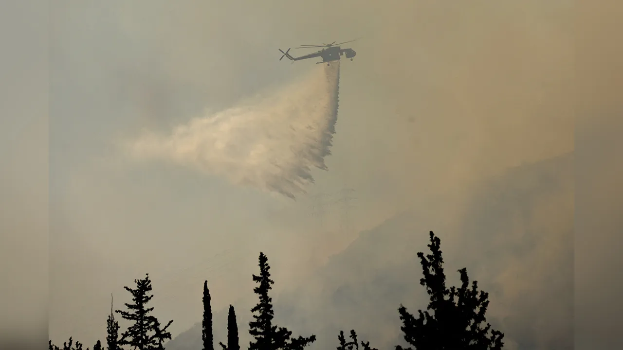 A firefighting helicopter makes a water drop as a wildfire burns near Haidari in Athens, Greece, July 31, 2026. REUTERS/Louiza Vradi
