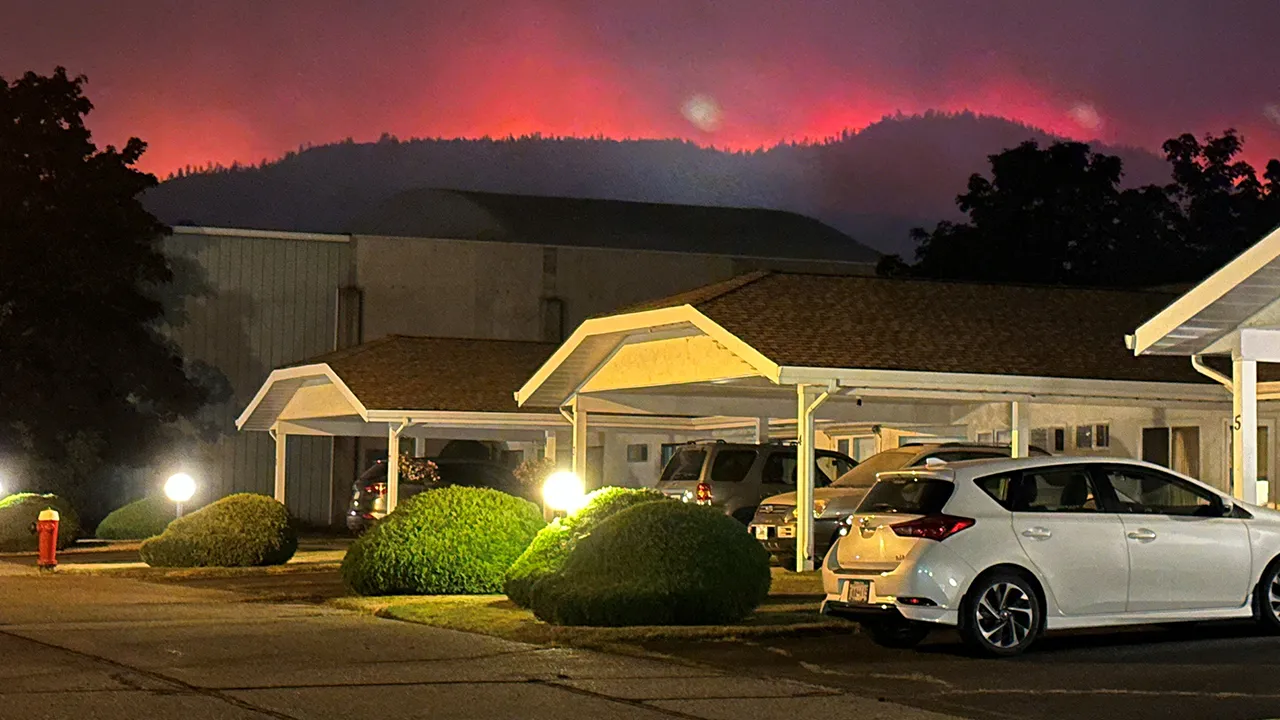 The Bald Range wildfire glows from behind hills near a residential street in Summerland, British Columbia, Canada, August 7, 2026. Picture taken with a mobile phone. Terry Fries/Handout via REUTERS. THIS IMAGE HAS BEEN SUPPLIED BY A THIRD PARTY. NO RESALES. NO ARCHIVES. MANDATORY CREDIT