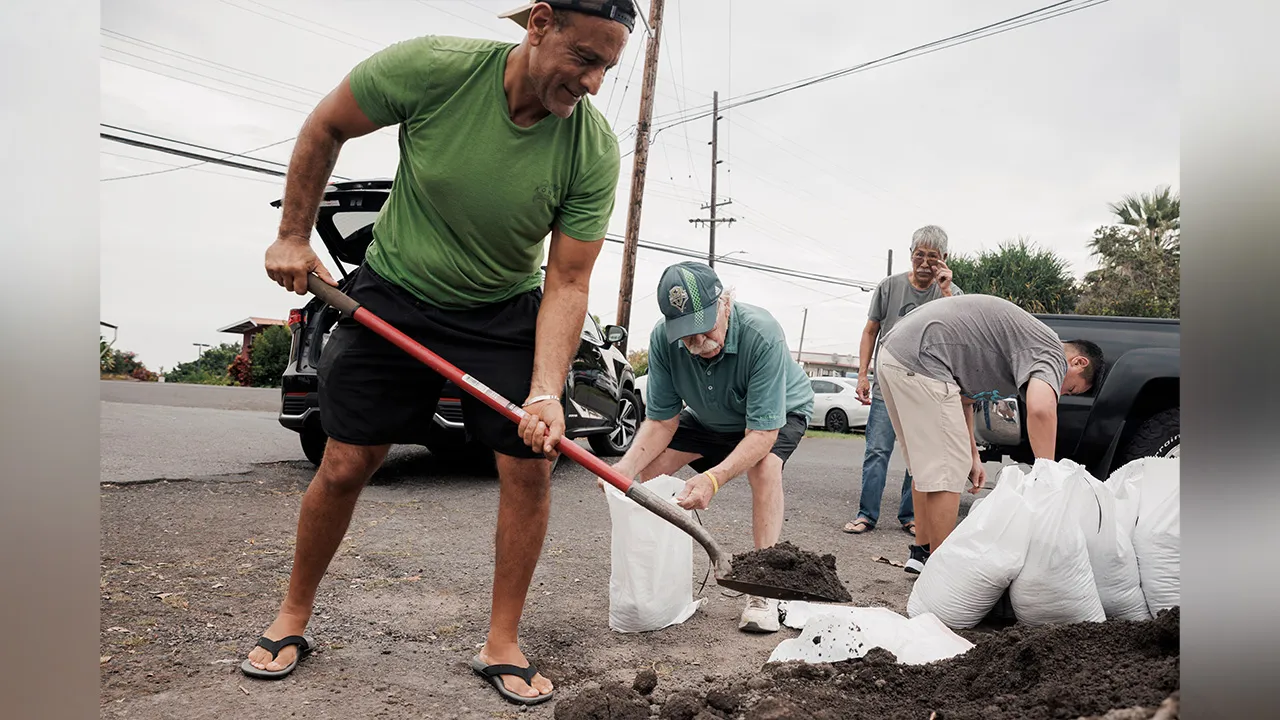 Shaheer Faltas, left, and his father-in-law, Joe Brosnan, fill sandbags in preparation for the arrival of Tropical Storm Lala in Captain Cook, Hawaii, Friday, Aug. 14, 2026. (Stephen Lam/San Francisco Chronicle via AP)