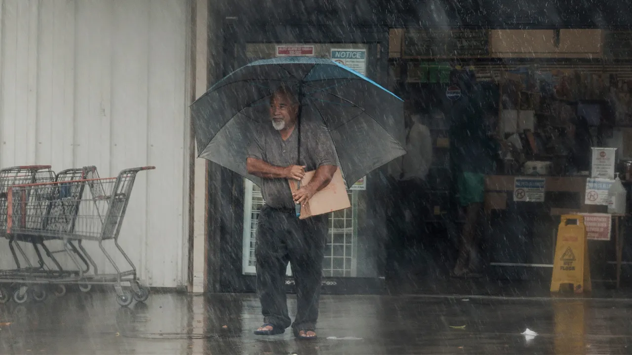 A resident carries supplies during Hurricane Lala in Hawaiian Ocean View, Hawaii, Saturday, Aug. 15, 2026. (Stephen Lam/San Francisco Chronicle via AP)