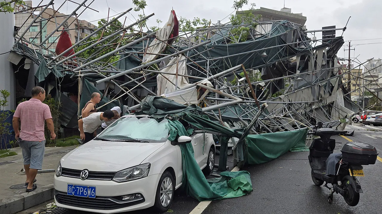 People look inside a car pinned by a fallen scaffolding structure after Typhoon Dolphin affected the area, in Wenzhou in eastern China's Zhejiang province, Monday, Aug. 10, 2026. (Chinatopix Via AP)